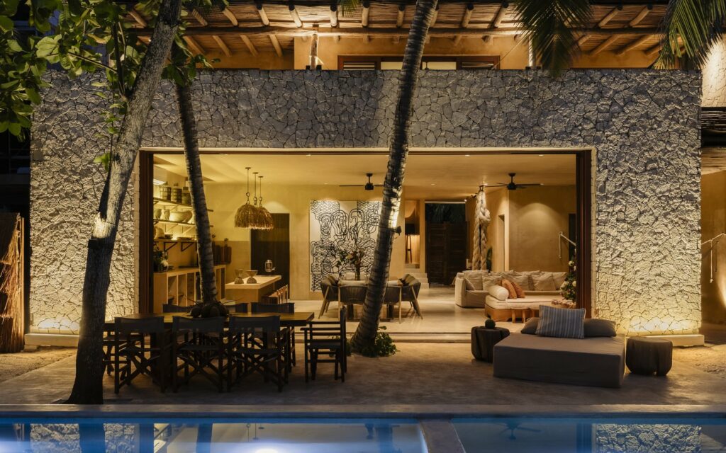 Villa Mariola lit from within at dusk, reflected in its pool — Soliman Bay, Tulum