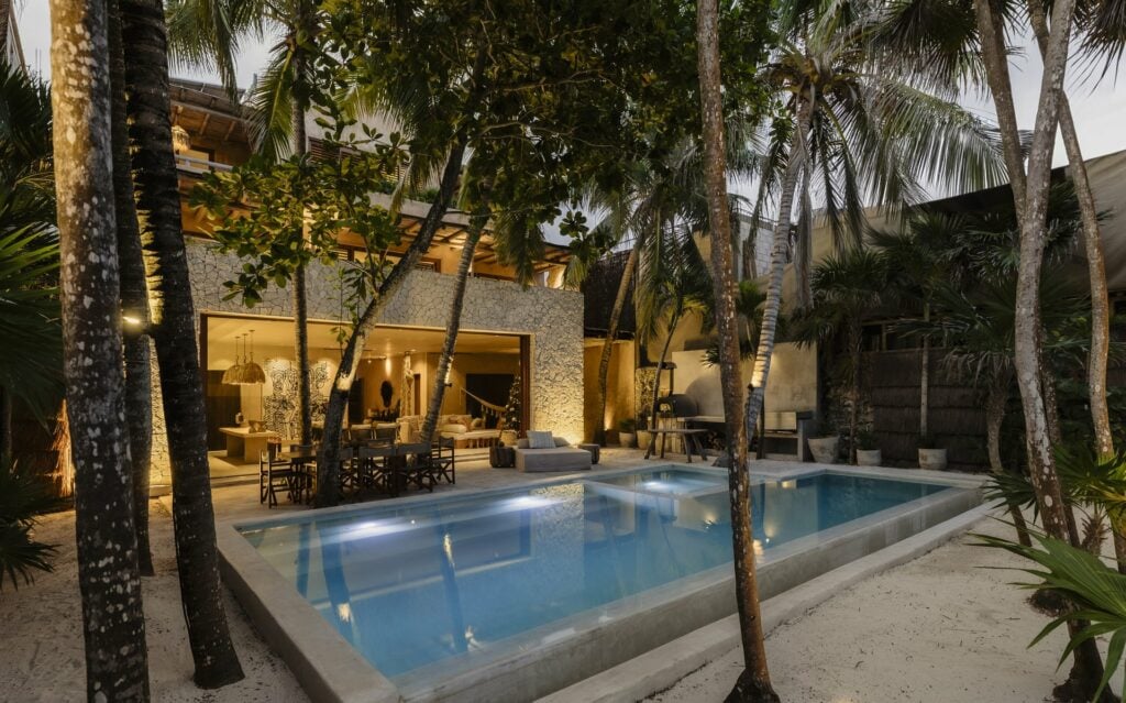 Villa Mariola pool at dusk with the villa lit within — Tulum, Mexico