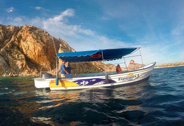 Boat tour approaching El Arco natural arch at Lands End where Pacific meets Sea of Cortez