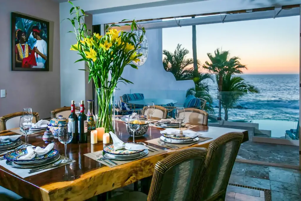 A table laid for dinner with flowers and candles on a terrace above the bay at sunset — Casa Karma
