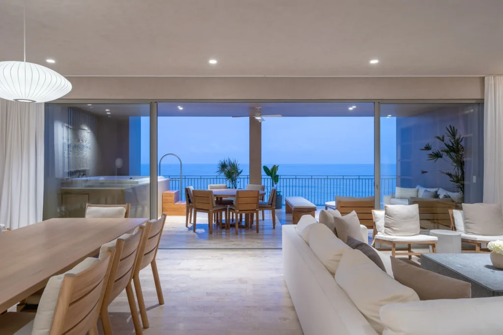 Condo Perla del Mar living and dining space open to the ocean at dusk — UAVI Beachfront Residences, Punta Mita