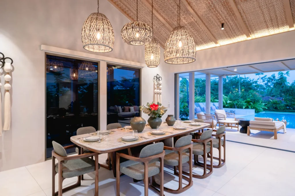 A dining table laid under pendant lights at dusk, the pool beyond — Villa Ceiba, Punta Mita