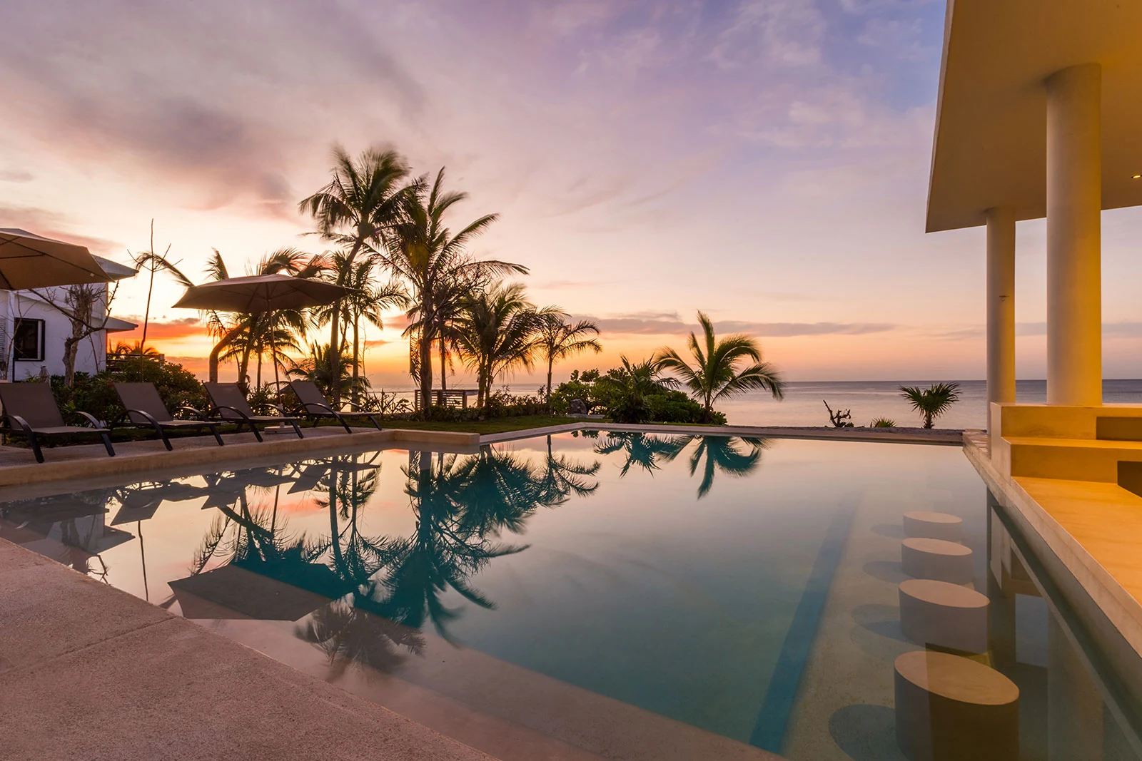 Casa Milah infinity pool and palm-lined beach at sunset — Half Moon Bay, Akumal, Mexico