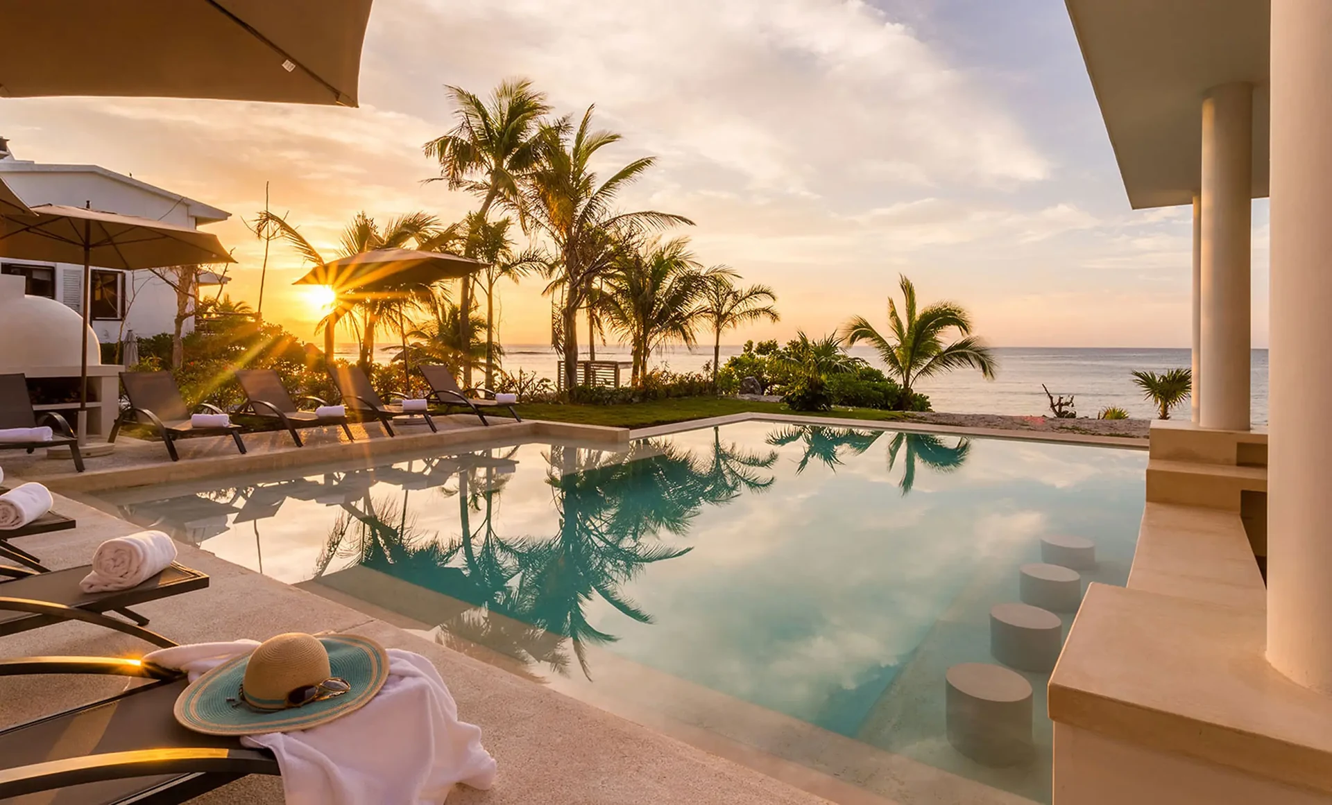 Casa Milah sunset reflecting across infinity pool beside palms — Half Moon Bay, Akumal, Mexico