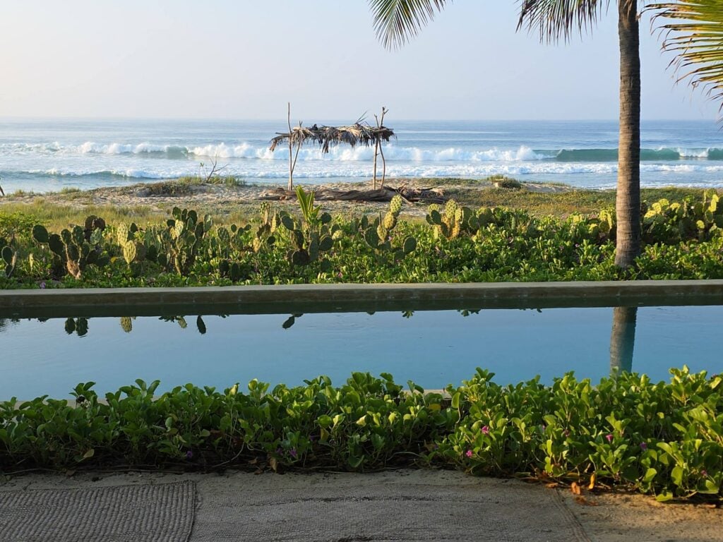 Garden running out into grey-gold sand at Casa U'undu, Ventanilla