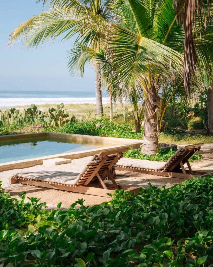 Sun loungers beside the beachfront pool at Casa U'undu, palms and the open Pacific behind, Puerto Escondido, Oaxaca