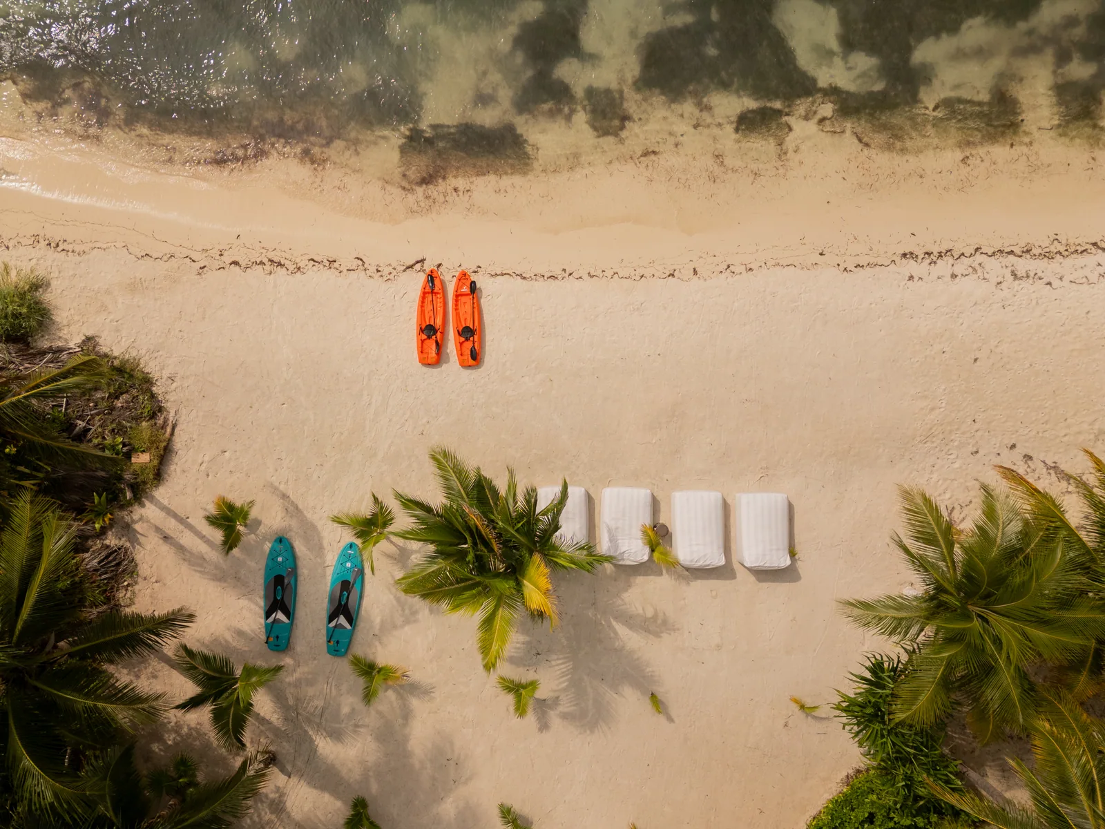 Kayaks, paddleboards and beach towels laid out on the sand, seen from above, Isla Mujeres