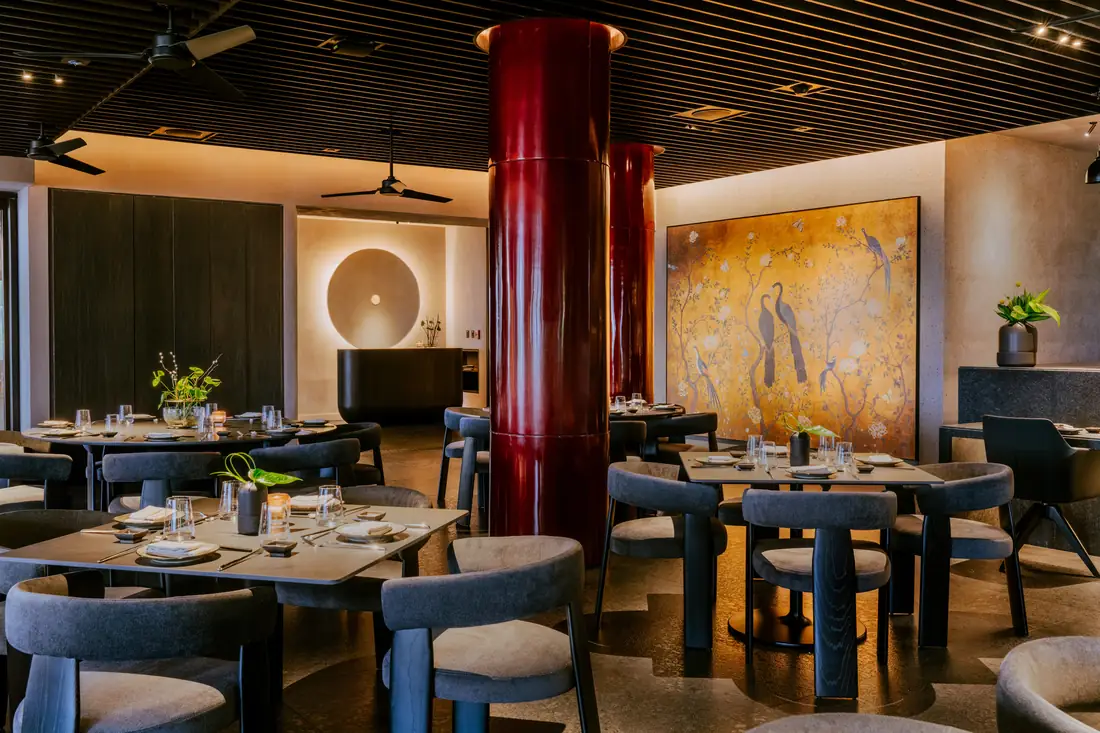 Aramara's redesigned dining room at Four Seasons Punta Mita, with a red lacquered column, dark wood tables and a large painting