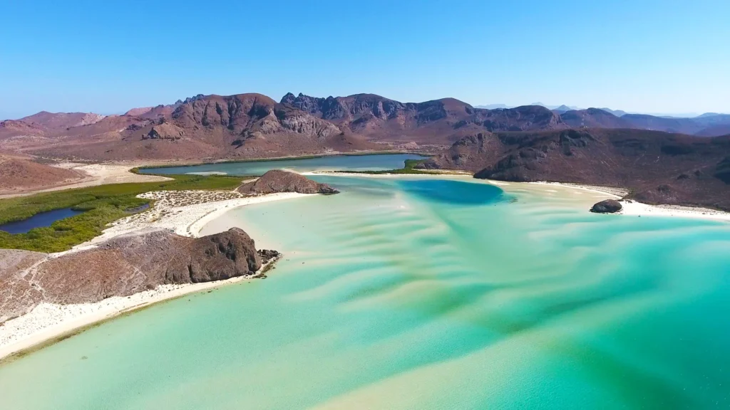 An aerial view of the turquoise shallows and white sandbars of Balandra beach.