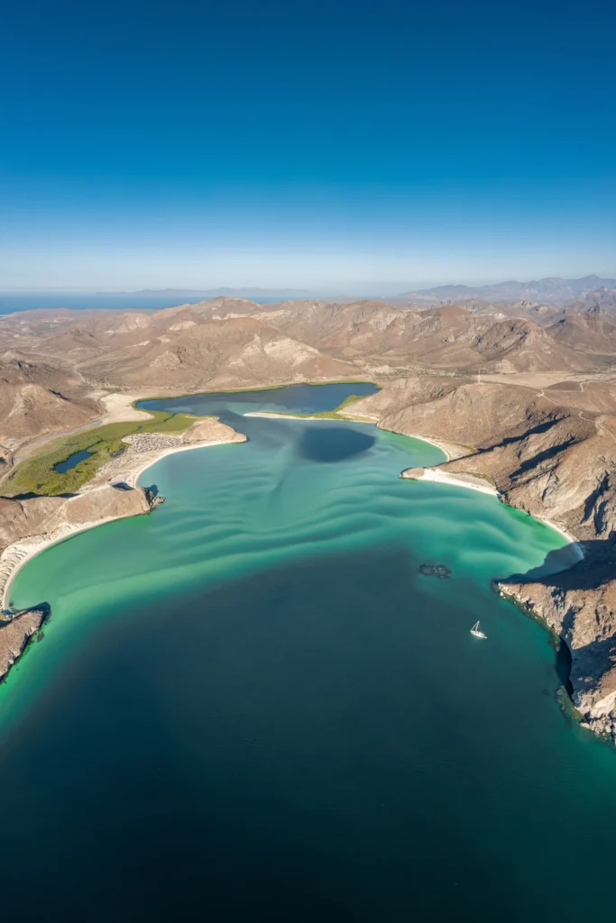 A vertical aerial view of Balandra lagoon, pale sand under clear green water.