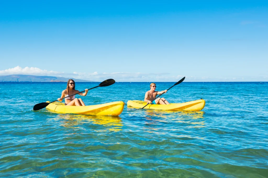 Two guests paddle yellow kayaks across clear shallow water at Balandra.