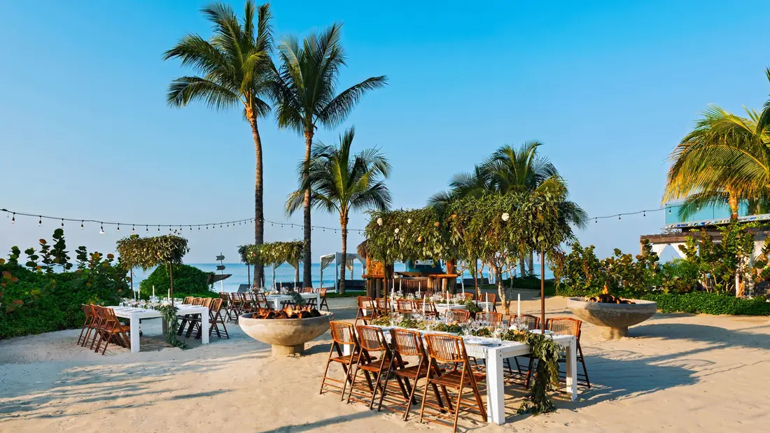 Long dinner tables on the sand under string lights at W Punta de Mita