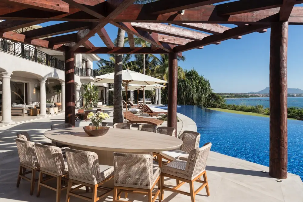 A long outdoor dining table under a pergola beside the pool at Casa La Vida, Punta Mita