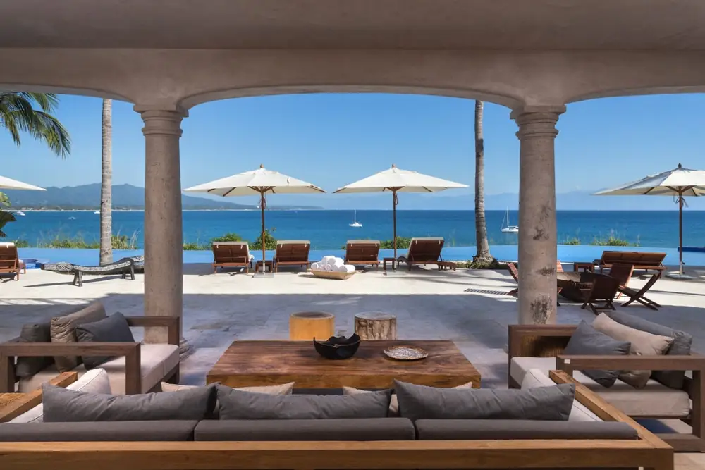 A covered terrace with sofas looking out to the sea at Casa La Vida, Punta Mita