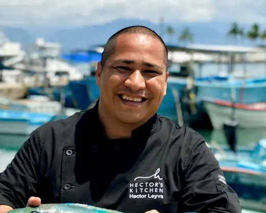 Chef Héctor Leyva of Zicatela and Hoja Santa, smiling in a chef's jacket at a marina