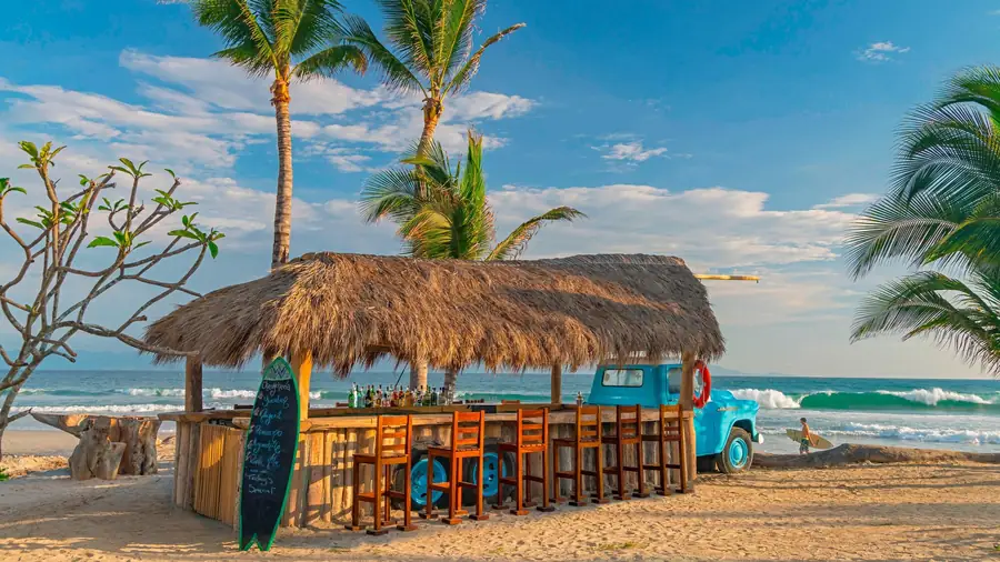 A vintage blue truck under a palapa bar on the beach: Chevychería at W Punta de Mita
