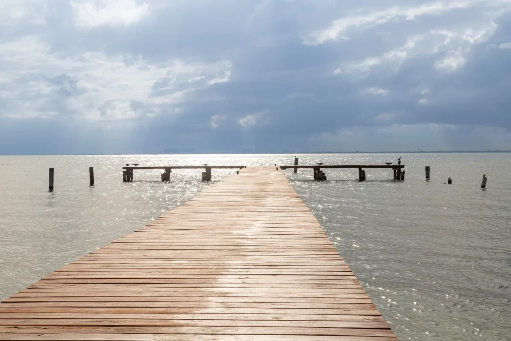 A wooden dock running out into the flat Bahía de Mujeres at first light