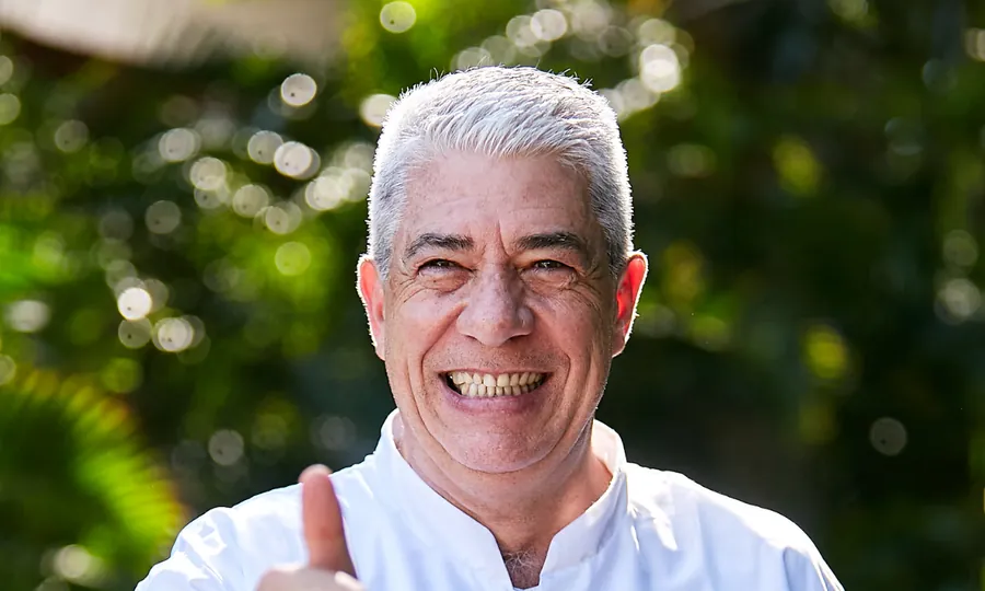 Thierry Blouet in a white chef's jacket giving a thumbs-up, green foliage behind
