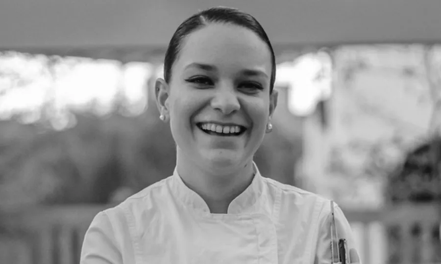 Black-and-white portrait of Vanessa Blouet smiling, in a white chef's jacket