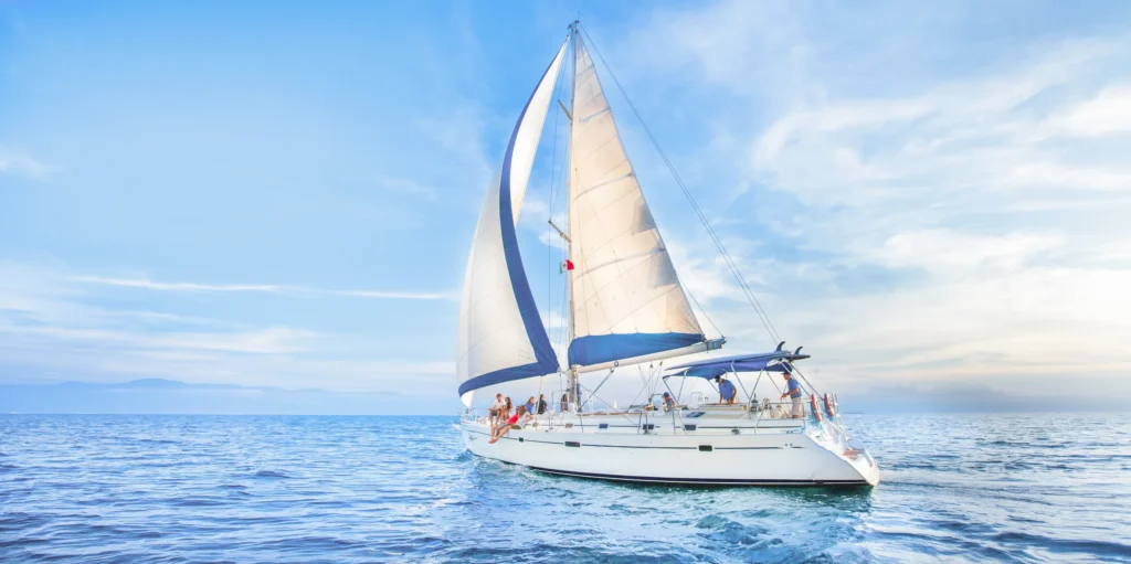 A sailing boat heels under full white sail with a cloud bank behind it.