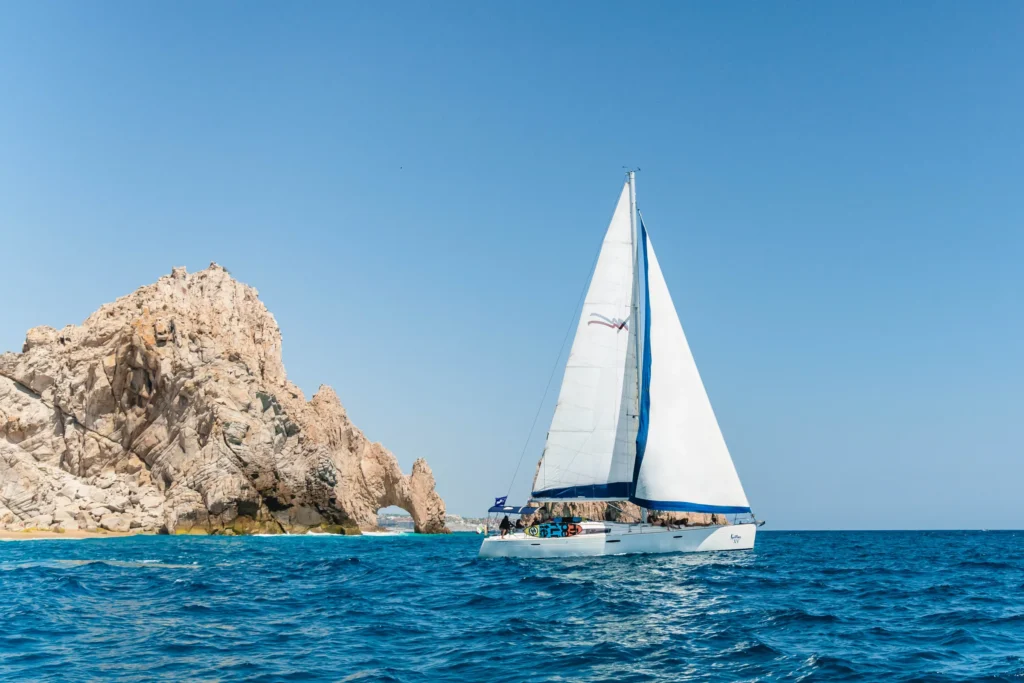 A sailing boat passes the granite rocks at Land’s End under full sail.