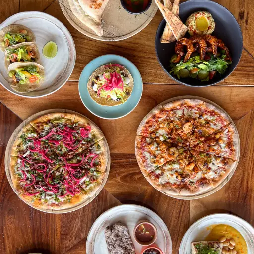 Wood-oven pizzas and seafood plates on a table at Pacífico Beach Club, Punta Mita