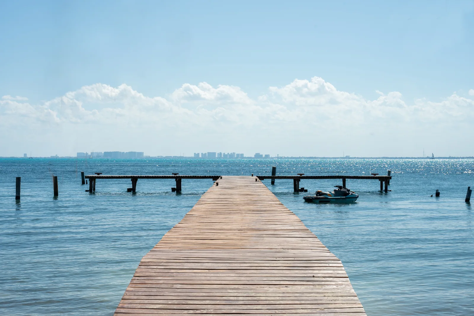 The private wooden dock at La Colección on Isla Mujeres, with the Cancún skyline across the bay