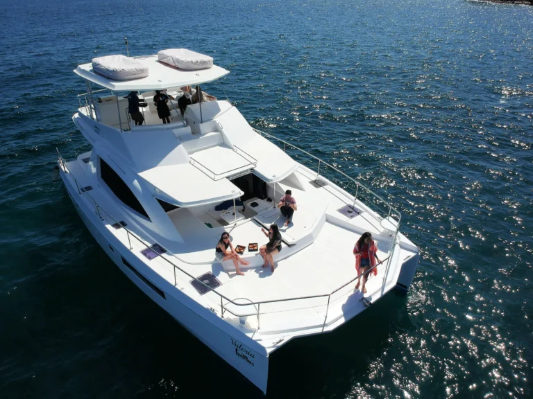 An aerial view of a power catamaran with guests on deck and in the water.