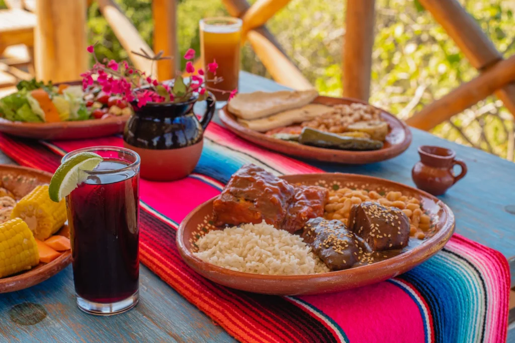 Mexican dishes in clay bowls on a bright woven cloth with a cold drink.