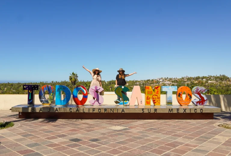 Large painted letters spelling the town name stand on a paved terrace by the sea.