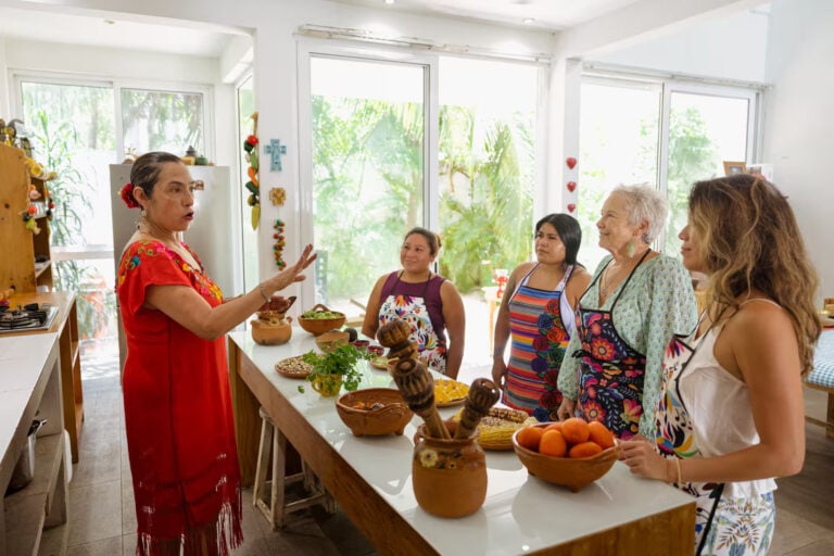 Host in traditional dress leading guests around the home kitchen counter