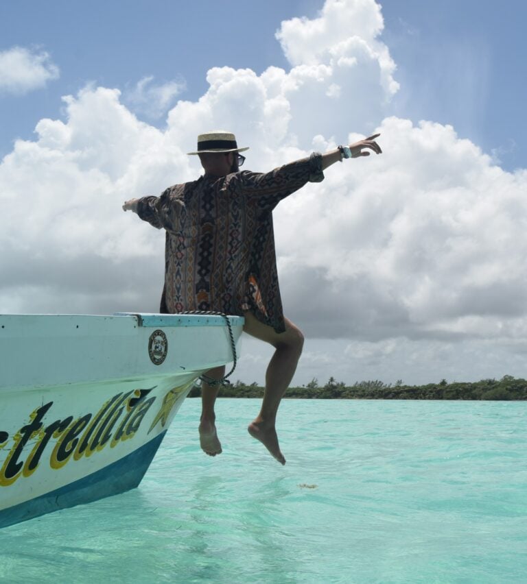 Guest seated on the bow of a boat over turquoise lagoon water in Sian Ka'an