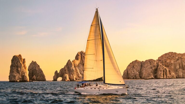 Sailboat at sunset in front of the Land's End rocks and El Arco