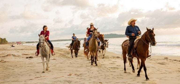 Group on horseback riding along the beach