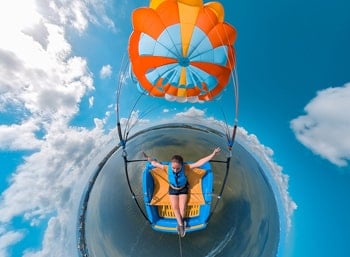 Fisheye shot of a rider in the Skyrider parasail seat under an orange-and-blue canopy