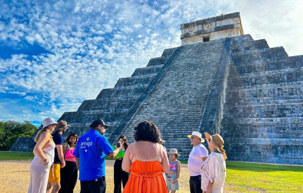 A guide leads a group of visitors in front of the El Castillo pyramid at Chichen Itza