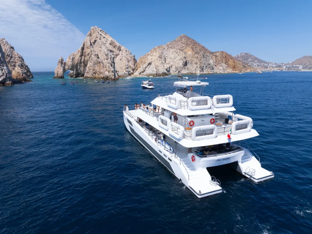 A catamaran passes in front of the pale granite headland at Land’s End.
