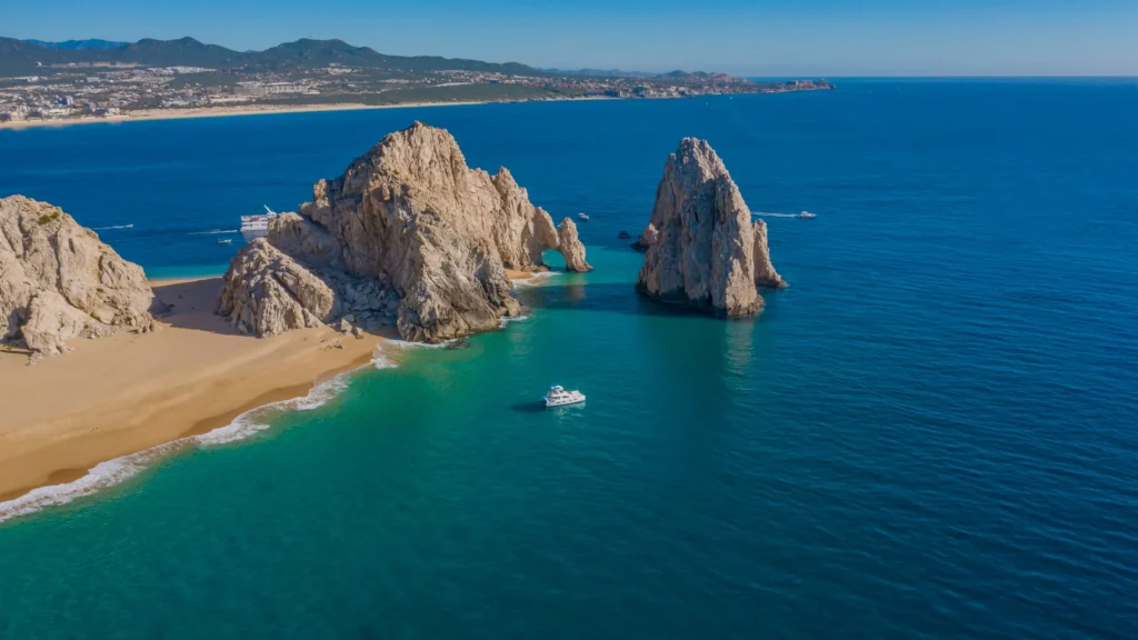 An aerial view of the granite headland at Land’s End with a boat in the bay.