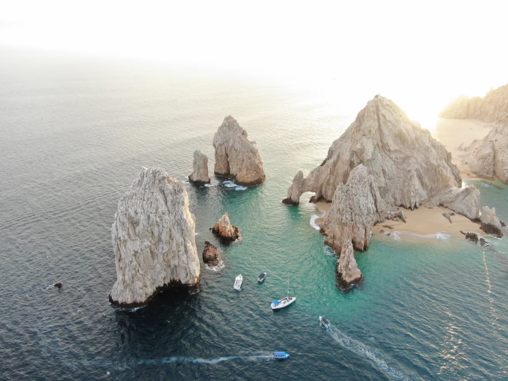 The headland and rocks at Land’s End seen from the air in low golden light.